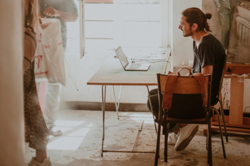 Man sitting at folding table with a laptop while construction happens around him | How to Plan a Kitchen Remodel Around Your Lifestyle
